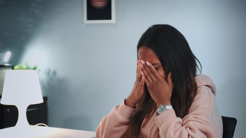 Woman sitting and covering her face with her hands