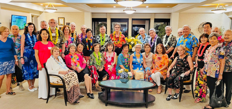 Image: People wearing floral necklaces and floral clothes posing for a photo. (Courtesy Edward Wan)