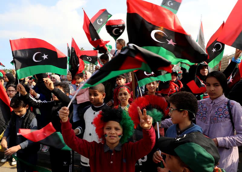 People wave Libyan flags as they gather during celebrations commemorating the 9th anniversary of the revolution at Martyrs' Square in Tripoli