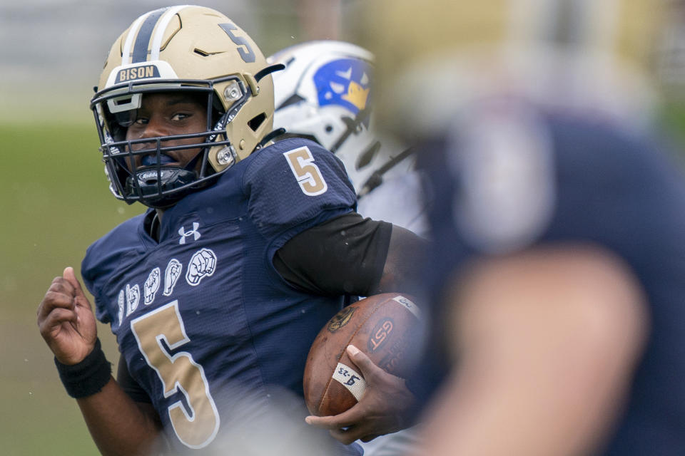 Gallaudet quarterback Brandon Washington, left, runs toward the end zone to make the first touchdown scored while wearing a football helmet that helps Deaf and hard-of-hearing players see play calls on a lens inside during an NCAA college football game against Hilbert College, Saturday, Oct. 7, 2023, in Washington. (AP Photo/Stephanie Scarbrough)