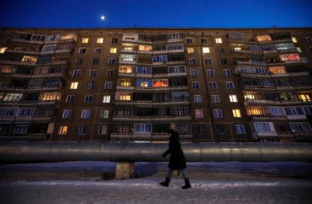 A woman walks past an apartment in the town of Aksu, north-eastern Kazakhstan, February 22, 2018.  REUTERS/Shamil Zhumatov