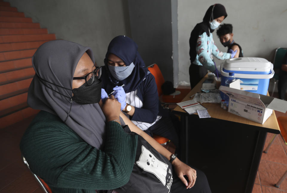 People receive a shot of the Sinovac vaccine for COVID-19 during a vaccination campaign at the Patriot Candrabhaga Stadium in Bekasi on the outskirts of Jakarta, Indonesia, Thursday, Oct. 28, 2021. Indonesians are looking ahead warily toward the upcoming holiday travel season, anxious for critical tourist spending but at the same time worried that an influx of millions of visitors could lead to a new coronavirus wave just as the pandemic seems to be getting better. (AP Photo/Achmad Ibrahim)