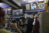 A woman drinks her espresso inside the Bar Nilo where a makeshift shrine of soccer legend and former Napoli player Diego Armando Maradona is displayed in downtown Naples, Italy, Wednesday, Sept. 18, 2019. Maradona achieved some of his most memorable exploits and in Naples is still revered with god-like status. (AP Photo/Gregorio Borgia)