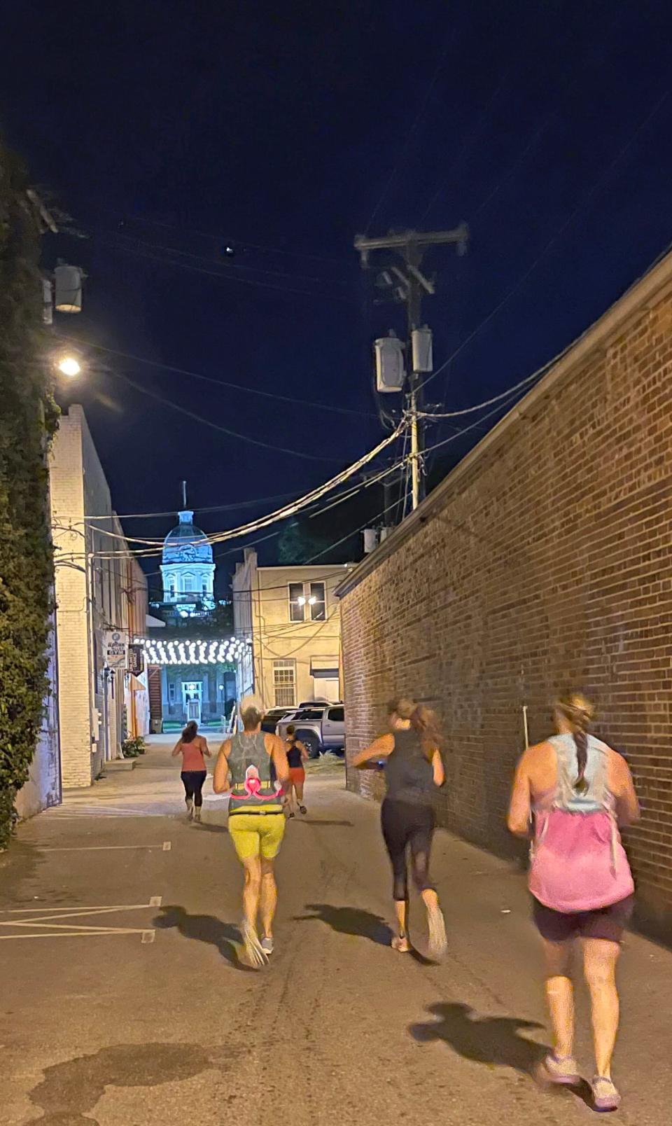 Runners head down a Shelby city street early Friday morning. The run was organized as a way to bring attention to safety for women and pay tribute to Eliza Fletcher, a Tennessee woman who was abducted and killed last week.