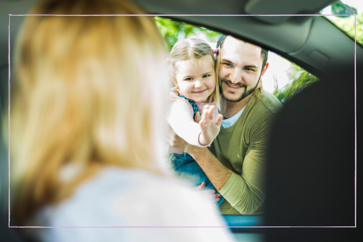  Smiling dad holding daughter waving goodbye to mum as she drives away. 