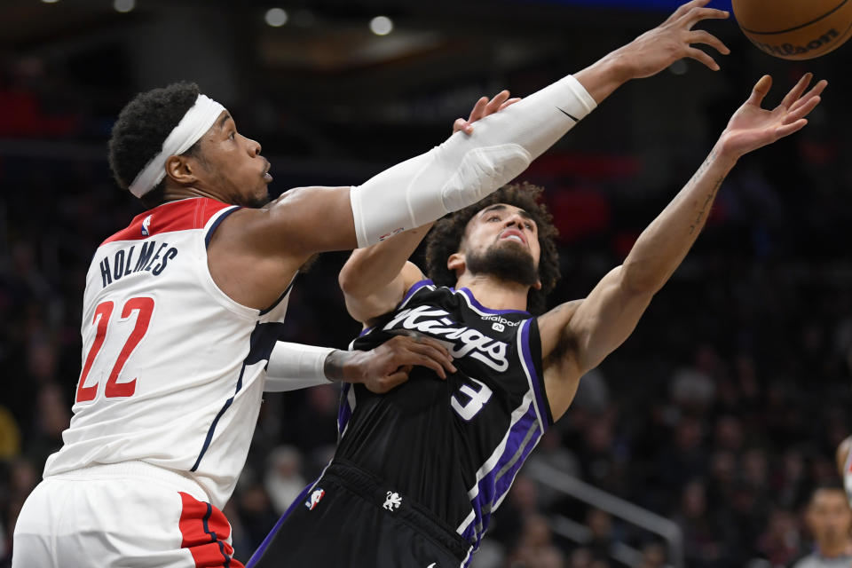 Washington Wizards forward Richaun Holmes, left, competes for a rebound against Sacramento Kings guard Chris Duarte during the second half of an NBA basketball game Thursday, March 21, 2024, in Washington. (AP Photo/John McDonnell)