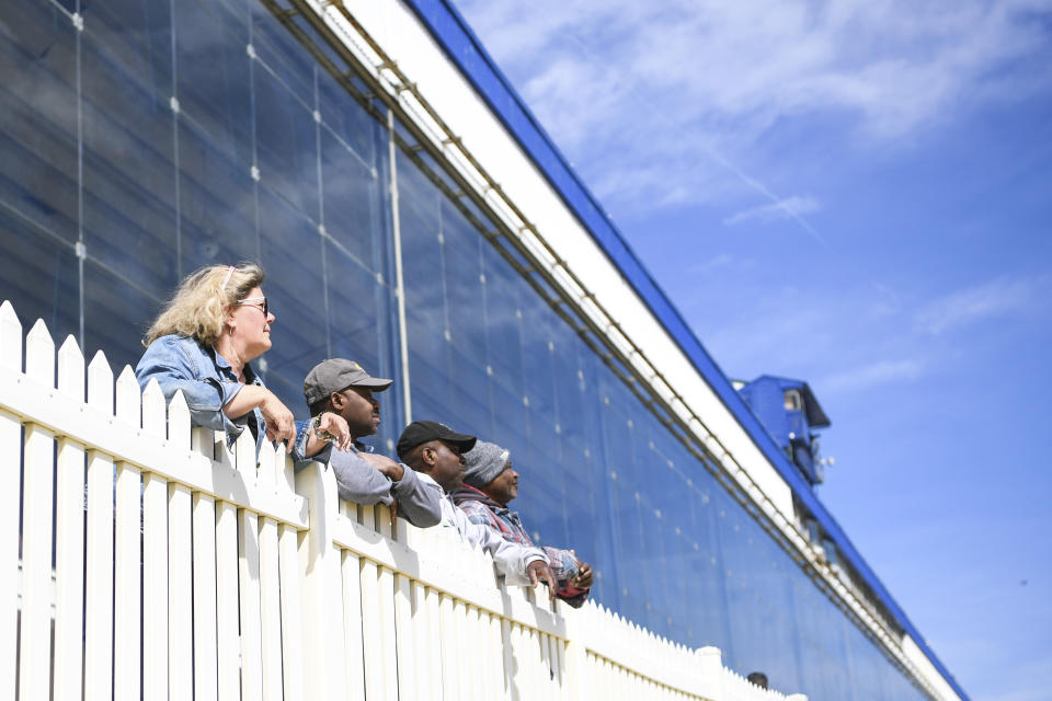Workers watch from the railing at Laurel Park Race Track as horse races are held without spectators, Saturday, March 14, 2020, in Laurel, Md. While most of the sports world is idled by the coronavirus pandemic, horse racing runs on. (AP Photo/Terrance Williams)