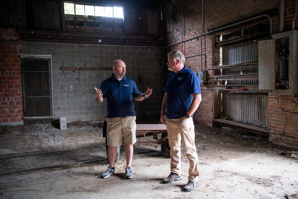 Company Distilling founder and president Kris Tatum, left, and master distiller Jeff Arnett, right, take the media on a tour on Monday, May 23, 2022, of a former brick factory in Alcoa that the distillery will eventually use to store barrels and have a tasting room, restaurant, retail store and outdoor entertainment space.