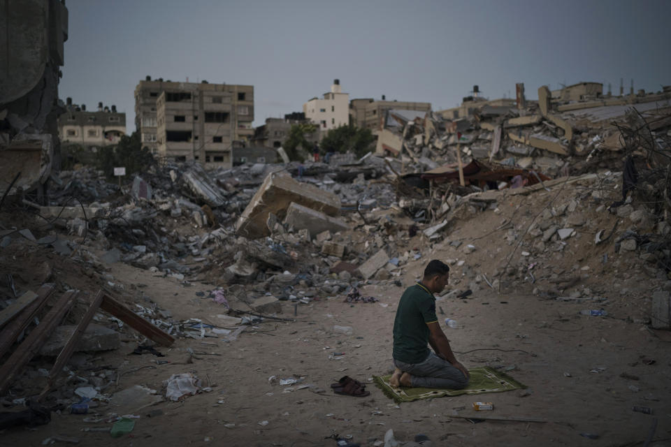 FILE - A Palestinian prays at dusk next to rubble of his family home, destroyed by an airstrike during an 11-day war between Hamas and Israel, in Beit Lahia, northern Gaza Strip, June 4, 2021. Investigators commissioned by the U.N.-backed Human Rights Council said Tuesday, June 7, 2022, that tensions between Palestinians and Israelis are underpinned by a feeling that Israel has embarked on a “perpetual occupation” of Palestinian areas with no intention of ending it. The findings came Tuesday in the first report by a Commission of Inquiry, set up last year following the war between Israel and Hamas in Gaza. (AP Photo/Felipe Dana, File)