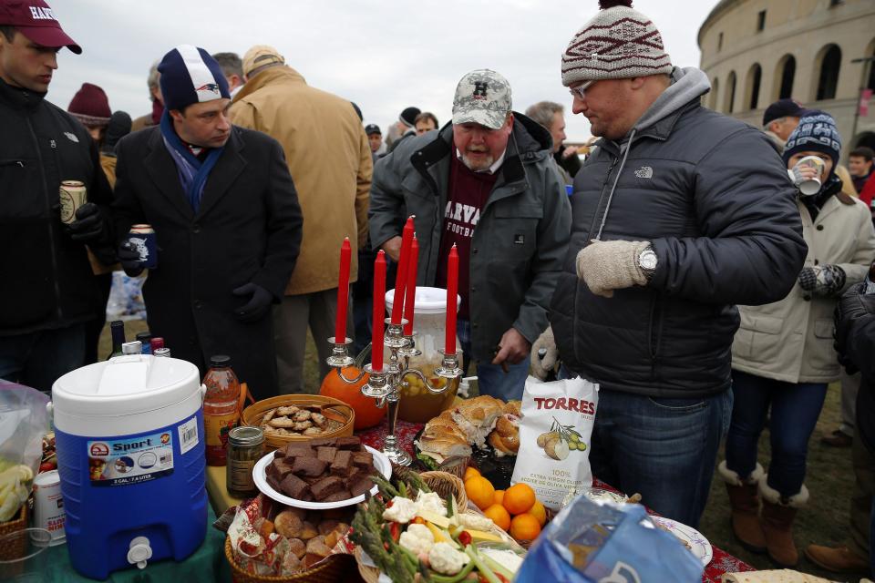 Harvard University football fans visit a tailgate party, complete with a candelabra, before their football game against Yale University at Harvard in Cambridge, Massachusetts November 22, 2014. Known as "The Game," the first Harvard versus Yale football game was played in 1875, making it one of the oldest rivalries in college sports. REUTERS/Brian Snyder (UNITED STATES - Tags: EDUCATION SPORT FOOTBALL FOOD)