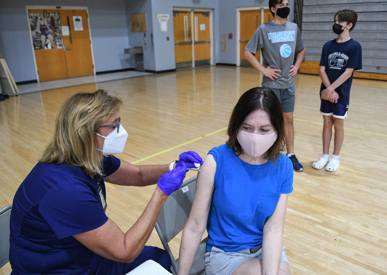 A nurse administers a shot of the Pfizer COVID-19 vaccine to Christine Tebbens at a vaccination clinic at Winter Springs High School in Winter Springs, Fla.