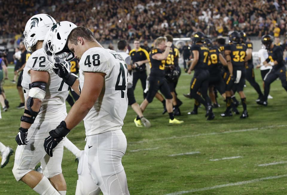 As Arizona State players celebrate a game-winning field goal, Michigan State defensive end Kenny Willekes (48) and defensive tackle Mike Panasiuk (72) walk off the field at the end of an NCAA college football game Saturday, Sept. 8, 2018, in Tempe, Ariz. Arizona State defeated Michigan State 16-13. (AP Photo/Ross D. Franklin)