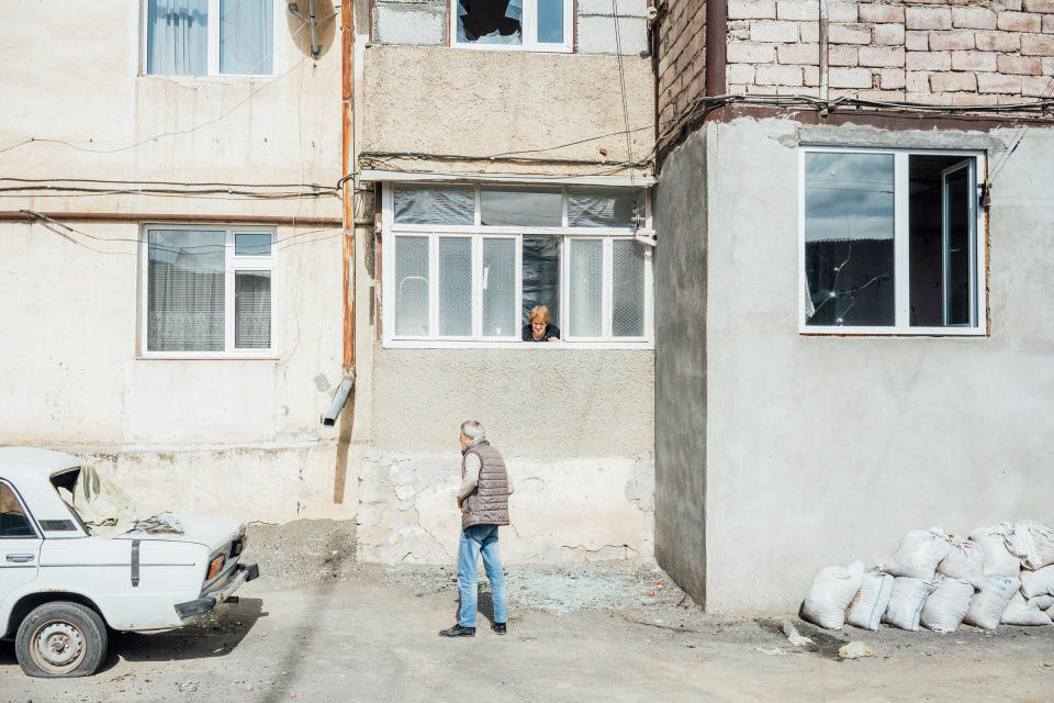 A woman speaks with a man through an open window of a shelled building in Stepanakert.<span class="copyright">Emanuele Satolli</span>