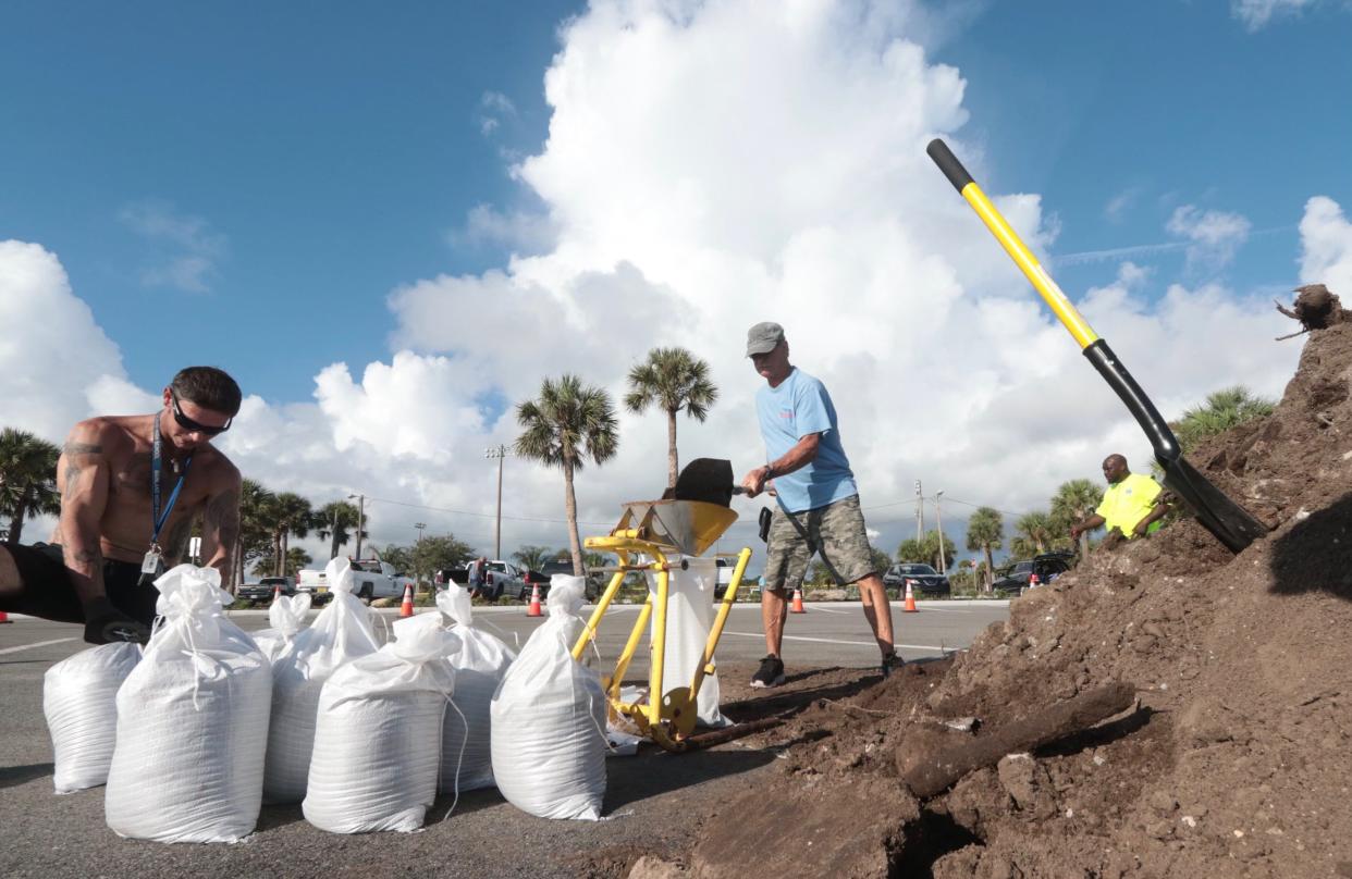 Travis Allen, left, and his father Tony Allen fill up sandbags at Bethune Point Park in Daytona Beach on Monday, Aug. 28, 2023.