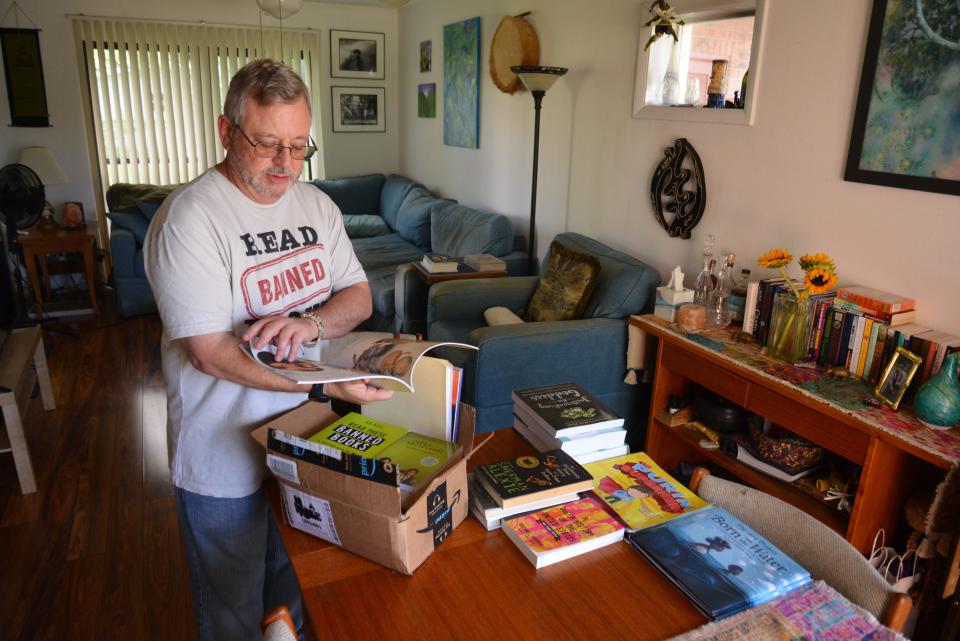 Adam Tritt, an AP English teacher at Bayside High School, is seen in his Melbourne home with a collection of banned books on his dining room table.