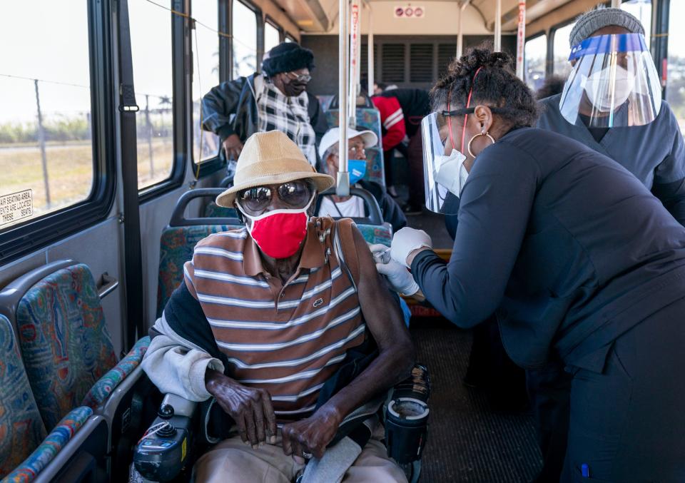 A senior receives a COVID-19 vaccine from a health care worker after arriving on a bus to a vaccination site at Anquan Boldin Stadium in Pahokee, Fla., on Feb. 3.