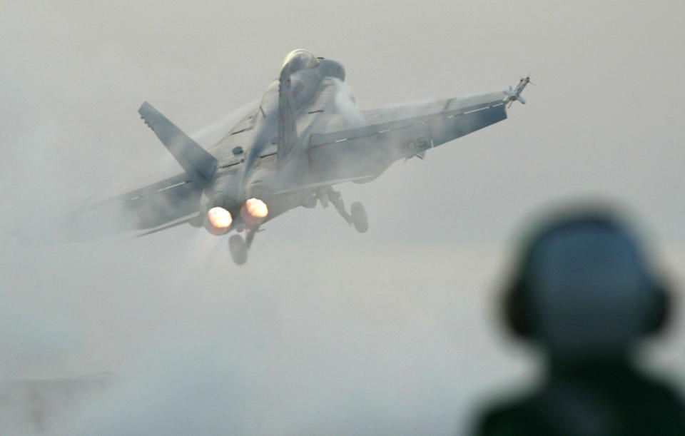 FILE - In this April 11, 2003 file photo, a flight deck handler watches as an F/A 18E Super Hornet is launched from the USS Nimitz in the Prsian Gulf. The Navy says a fighter jet has crashed in the Mojave Desert but its pilot safely ejected. The F/A-18E Super Hornet from Naval Air Station Lemoore in California's Central Valley went down Tuesday, Oct. 20, 2020 in Superior Valley south of Naval Air Weapons Station China Lake. (AP Photo/Richard Vogel, File)