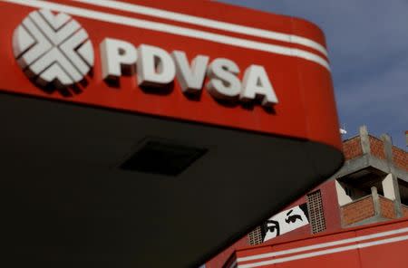 FILE PHOTO: A painting depicting the eyes of Venezuela's late President Hugo Chavez, is pictured close to a corporate logo of the state oil company PDVSA at a gas station in Caracas, Venezuela, October 10, 2017. REUTERS/Ricardo Moraes/File Photo