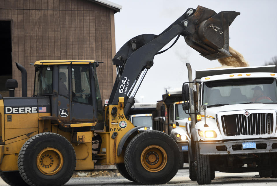 In this Sunday, Dec. 1, 2019 photo, a front end loader dumps salt into a waiting truck, as others line up in preparation for a snow storm at the DPW yard in Worcester, Mass. A wintry storm that made Thanksgiving travel miserable across much of the country gripped the East with a messy mixture of rain, snow, sleet and wind. (Christine Peterson/Worcester Telegram & Gazette via AP)