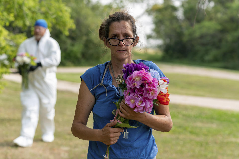 Ruby Works stands for a photograph before bringing flowers to the home of a victim who has been identified by residents as Wes Petterson in Weldon, Saskatchewan, on Monday, Sept. 5, 2022. Works said that the 77-years-old victim was like an uncle to her. Saskatchewan RCMP say arrest warrants have been issued for two suspects in a deadly stabbing rampage who remain at large. (Heywood Yu/The Canadian Press via AP)