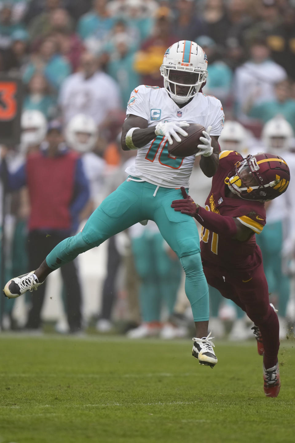 Miami Dolphins wide receiver Tyreek Hill, left, catches a pass in front of Washington Commanders safety Kamren Curl during the first half of an NFL football game Sunday, Dec. 3, 2023, in Landover, Md. (AP Photo/Mark Schiefelbein)