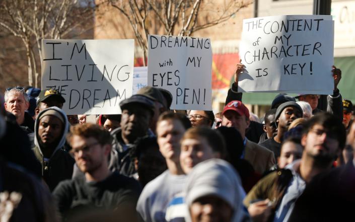 Marchers hold up signs during the Unity March honoring Martin Luther King Jr. Monday, Jan. 15, 2018 in Tuscaloosa. [Staff Photo/Gary Cosby Jr.]