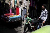 In this June 23, 2019, photo, a young worker pulls his hand cart in the main bazaar in Tehran, Iran. The most-visible place to see the effect of the economic hardship most face comes from walking by any money-exchange shop. Depreciation and inflation makes everything more expensive, from fruits and vegetables to tires and oil all the way to the big-ticket items, like mobile phones. (AP Photo/Ebrahim Noroozi)