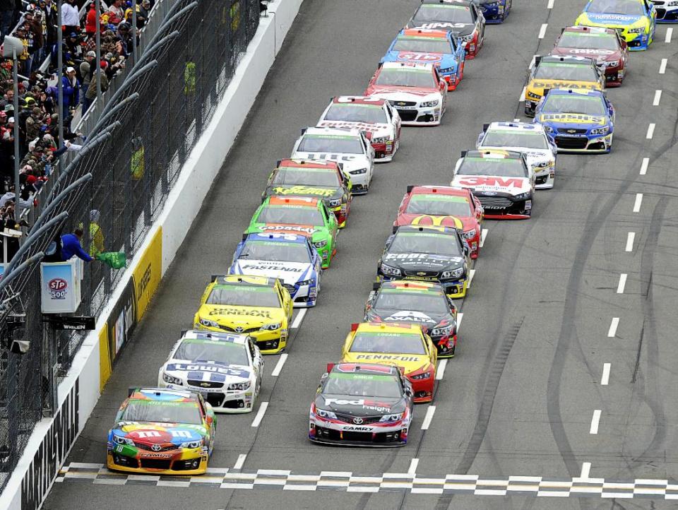 Driver Kyle Busch (18) leads the field to the green flag for the start of a NASCAR Sprint Cup Series auto race at Martinsville Speedway, Sunday, March 30, 2014, in Martinsville, Va. (AP Photo/Mike McCarn)