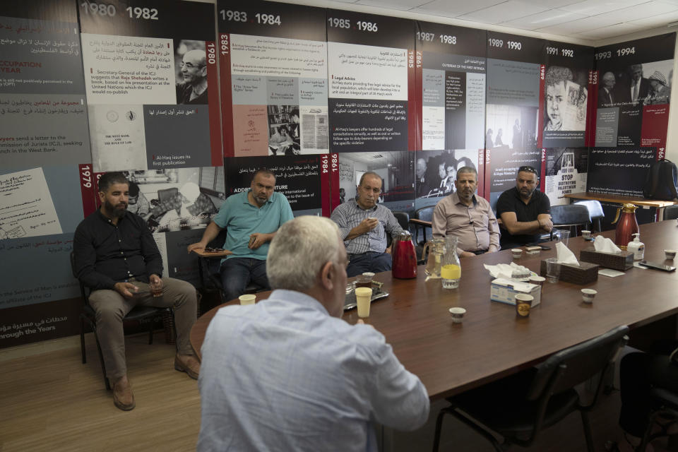 Shawan Jabarin, director of al-Haq Human rights organization, front, briefs activists who gathered to show support, at his office that was raided by Israel forces, in the West Bank city of Ramallah, Thursday, Aug. 18, 2022. Israel raided the offices of several Palestinian advocacy groups it had previously designated as terrorist organizations, sealing entrance doors and leaving notices declaring them closed, the groups said Thursday. (AP Photo/Nasser Nasser)