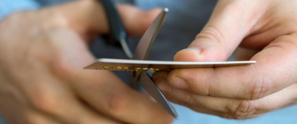 Man cutting gold credit card with scissors.