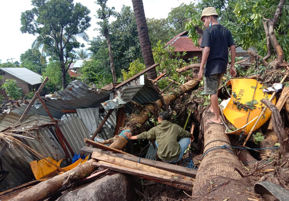 Indonesian scavenge usable items from the ruins of their house at a village hit by a landslide in Ile Ape Timur on Lembata Island, East Nusa Tenggara province, Indonesia, Monday, April 5, 2021. Multiple disasters caused by torrential rains in eastern Indonesia and neighboring East Timor have left a number of people dead or missing as rescuers were hampered by damaged bridges and roads and a lack of heavy equipment Monday. (AP Photo/Ricko Wawo)