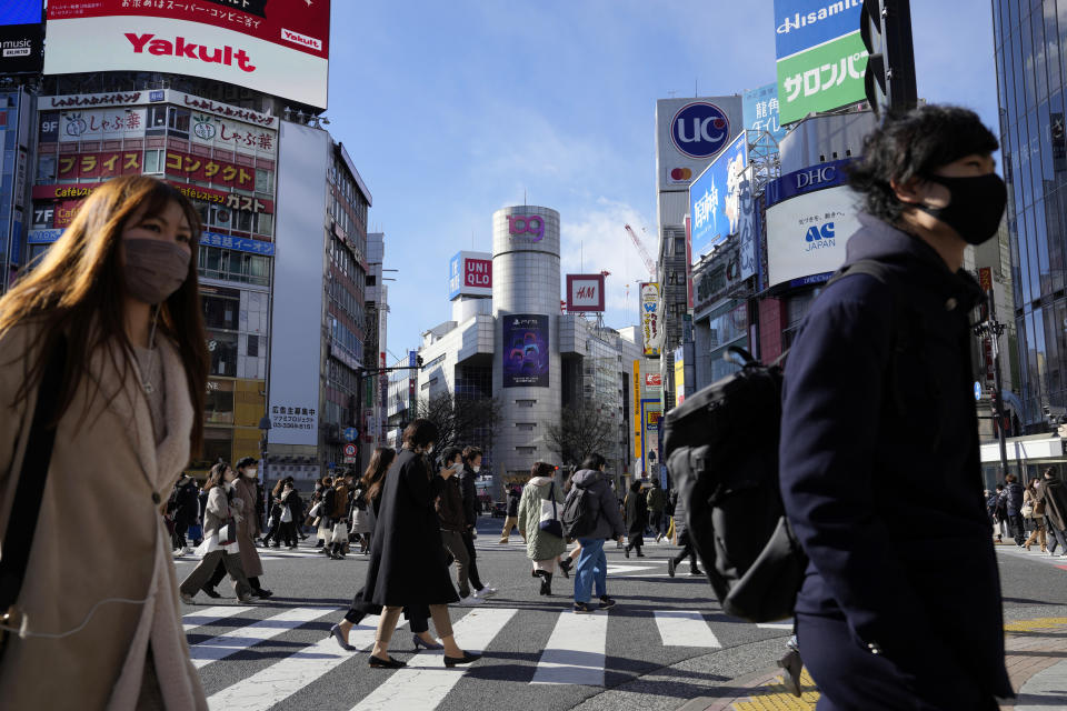 People wearing protective masks to help curb the spread of the coronavirus walk along a pedestrian crossing Friday, Jan. 21, 2022, in Tokyo. Restaurants and bars will close early in Tokyo and a dozen other areas across Japan beginning Friday as the country widens COVID-19 restrictions due to the omicron variant causing cases to surge to new highs in metropolitan areas. (AP Photo/Eugene Hoshiko)