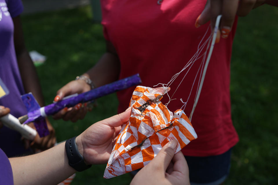 Girls examine a lightly burned parachute post-launch, likely due to a gap in recovery wadding — a fire-resistant, paper-like substance that’s stuffed in the model. “You don’t often think of it as a huge part of the system, but it shields your parachute from being burned by the explosion; it’s essential to the rocket landing safely,” Sonali Fiorillo explains. (Marianna McMurdock)