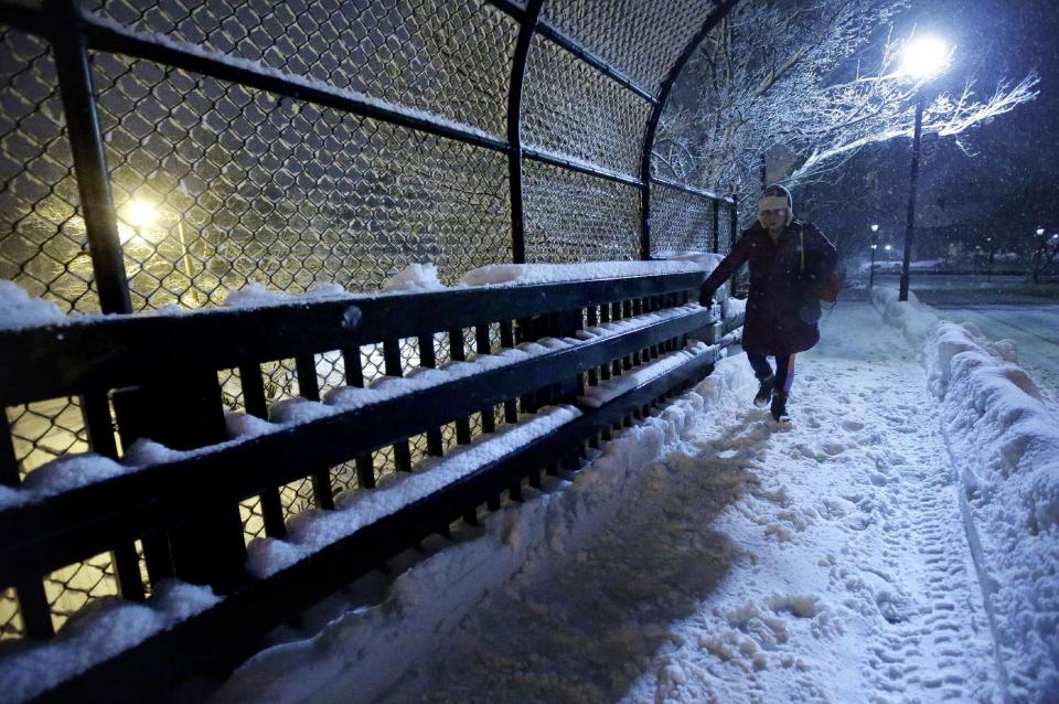 A person walks on a snow-covered sidewalk on a bridge near a commuter rail station Sunday, Feb. 12, 2017, in Wellesley, Mass. Another winter blast of snow and strong winds moved into the Northeast on Sunday to the delight of some and the consternation of others, just days after the biggest storm of the season dumped up to 19 inches of snow in the region. (AP Photo/Steven Senne)