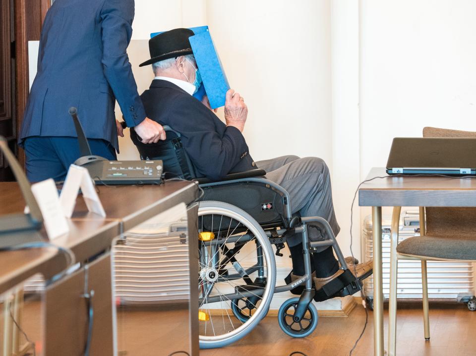Bruno Dey, a former SS-watchman at the Stutthof concentration camp, hides his face behind a folder as he arrives on a wheelchair for a hearing in his trial on July 23, 2020 in Hamburg, northern Germany. - The 93-year-old former Nazi concentration camp guard was handed a suspended sentence of two years in prison as a court in Hamburg found him guilty of complicity in WWII atrocities. In what could be one of the last such cases of surviving Nazi guards, Bruno Dey was convicted for his role in the killing of 5,230 people when he was a teenaged SS tower guard at the Stutthof camp near what was then Danzig, now Gdansk, in Poland. (Photo by Daniel Bockwoldt / POOL / AFP) / The erroneous mention[s] appearing in the metadata of this photo by Daniel Bockwoldt has been modified in AFP systems in the following manner: PIXEL CORRECTION - Resending unpixelated version of the photo, as the court does not request to make the defendant unrecognisable. Please immediately remove the erroneous mention[s] from all your online services and delete it (them) from your servers. If you have been authorized by AFP to distribute it (them) to third parties, please ensure that the same actions are carried out by them. Failure to promptly comply with these instructions will entail liability on your part for any continued or post notification usage. Therefore we thank you very much for all your attention and prompt action. We are sorry for the inconvenience this notification may cause and remain at your disposal for any further information you may require. (Photo by DANIEL BOCKWOLDT/POOL/AFP via Getty Images)