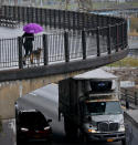 A woman walks with a dog along Brooklyn Heights Promenade while traffic travels beneath, Friday April 5, 2019, in New York. The promenade makes up the top deck overhang of a deteriorating Brooklyn-Queens Expressway and the city's plans for repairs has drawn neighborhood protest, since it calls for a temporary six lane highway on the promenade. (AP Photo/Bebeto Matthews)