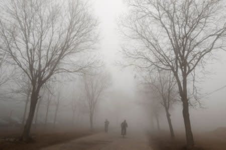 FILE PHOTO: People are seen amid heavy fog on the outskirts of Changzhi, Shanxi province March 19, 2010. REUTERS/Stringer/File Photo