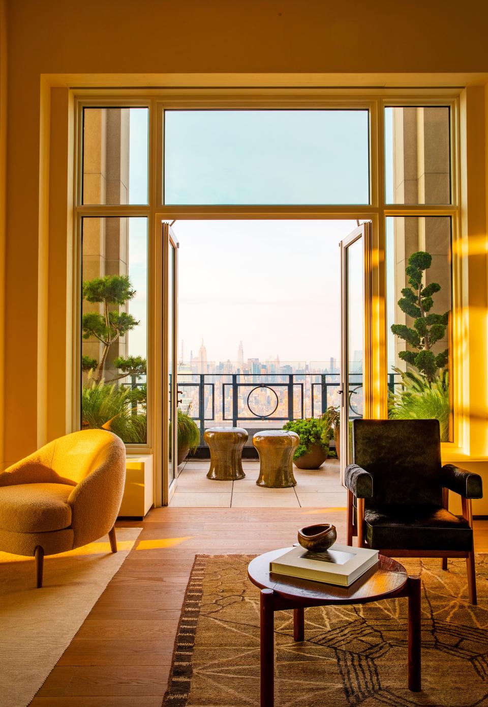 The living room looks out on a terrace landscaped by Harrison Green. Stools by Hun-Chung Lee. At one end of the living room, a chair from the high Court in Chandigarh, India, a unique Dienst + Dotter bowl, and a Pierre Jeanneret cocktail table sit on a circa-1940 rug.