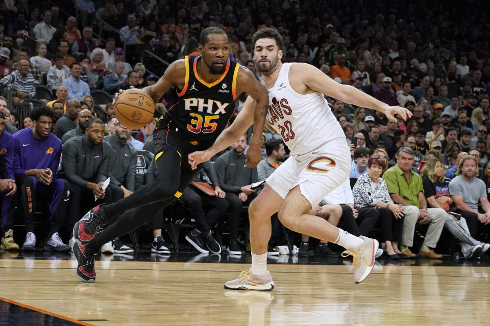 Phoenix Suns forward Kevin Durant (35) drives around Cleveland Cavaliers forward Georges Niang (20) during the first half of an NBA basketball game in Phoenix, Wednesday, April. 3, 2024. (AP Photo/Darryl Webb)