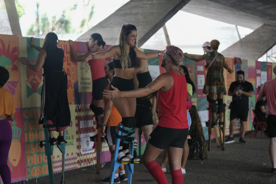 A workshop participant is shadowed by a volunteering former student during a stilt walking class led by instructor Raquel Potí, at the Museum of Modern Art in Rio de Janeiro, Brazil, Saturday, Jan. 27, 2024. Potí is chiefly responsible for the explosion of stilt walking in Rio, having trained more than 1,000 kids and adults over the past decade. (AP Photo/Silvia Izquierdo)