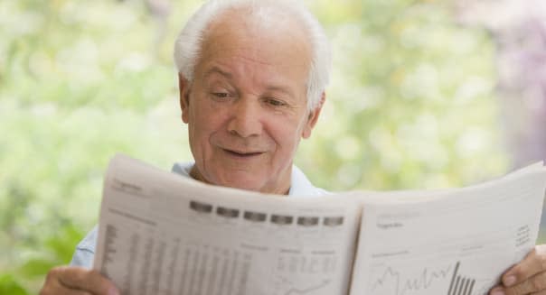 Senior Hispanic man reading financial newspaper