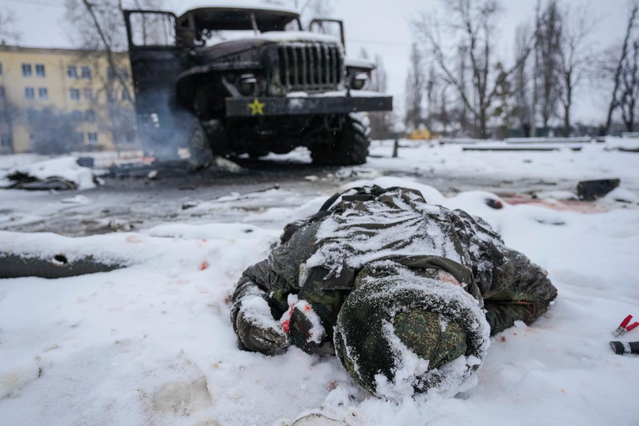FILE - The body of a serviceman is coated in snow next to a destroyed Russian military multiple rocket launcher vehicle on the outskirts of Kharkiv, Ukraine, on Feb. 25, 2022. 