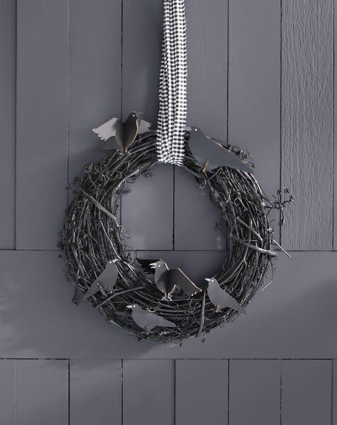 <p>Wreaths aren't just for doors. We love the idea of hanging a wreath, like this black crow grapevine version, above a mantel as a spooky holiday focal point. Layer one over a mirror, or if space allows, hang a trio for maximum impact.</p>