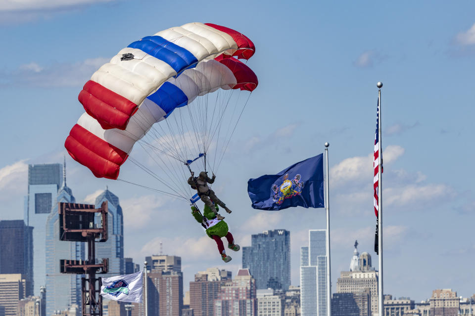 The Phillie Phanatic parachutes past the Philadelphia skyline and onto the field before the start of the Philadelphia Phillies home opener baseball game against the Oakland Athletics, Friday, April 8, 2022, in Philadelphia. (AP Photo/Laurence Kesterson)