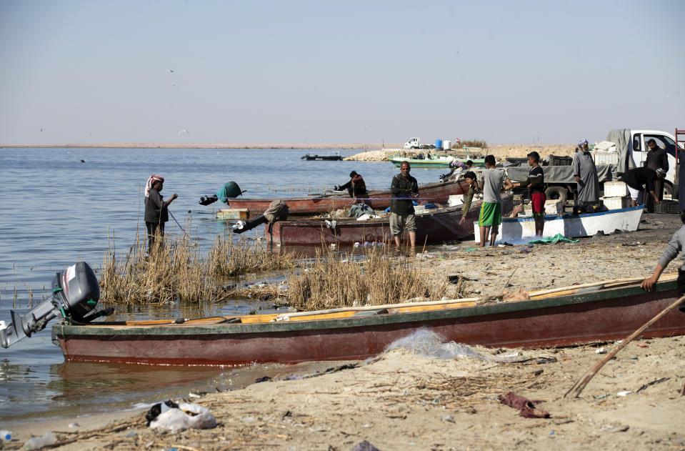 Fishermen stand on the bank of Razzaza Lake, also known as Lake Milh, Arabic for salt, in the Karbala governorate of Iraq, Feb. 14, 2022. The lake was once a tourist attraction known for its beautiful scenery and an abundance of fish that locals depended on. Dead fish now litter its shores and the once-fertile lands around it have turned into a barren desert. (AP Photo/Hadi Mizban)