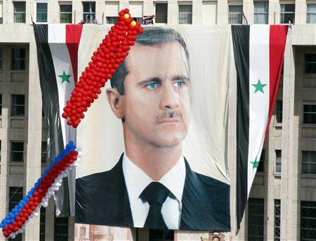 A larger banner of Syrian President Bashar al-Assad hangs from central bank during a rally of his supporters at al-Sabaa Bahrat square in Damascus October 12, 2011. REUTERS/ Khaled al-Hariri