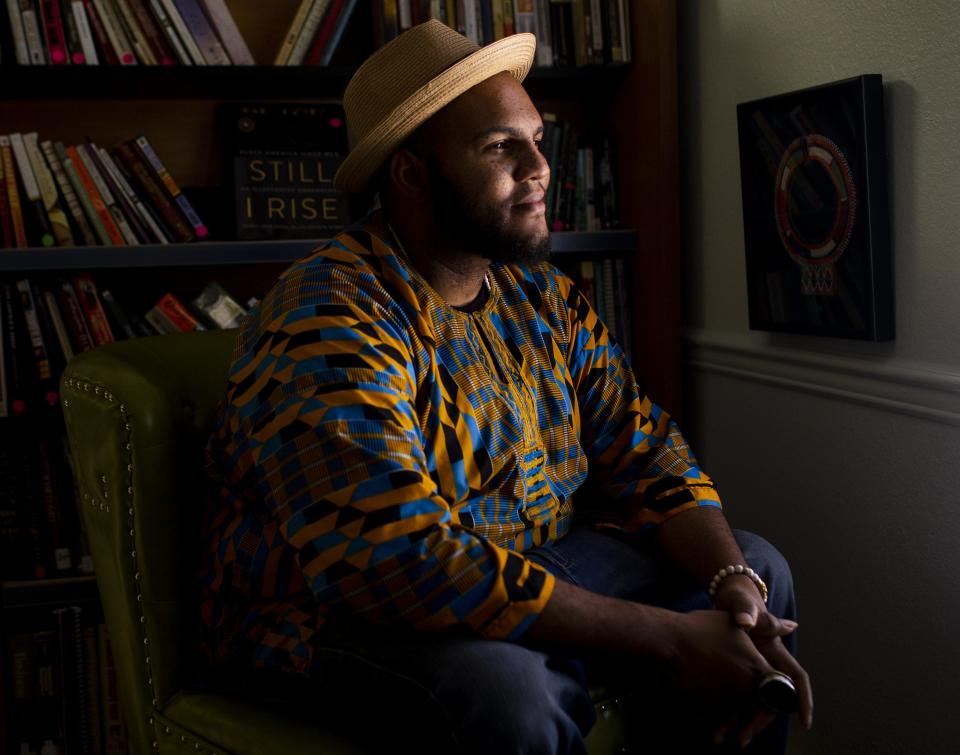 Ali Nervis, the owner of Grassrootz Bookstore, sits in front of a bookshelf inside his store in Phoenix on July 10, 2020.