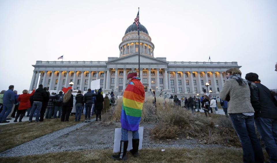 A supporter of gay marriage Tiffany Lundeen wears a flag during a rally at the Utah State Capitol, Tuesday, Jan. 28, 2014, in Salt Lake City. Opponents and supporters of gay marriage held twin rallies at the Capitol on Tuesday. More than 1,000 gay couples rushed to get married when a federal judge overturned Utah's constitutional amendment banning same-sex marriage in late December 2013. In early January the U.S. Supreme Court granted Utah's request for an emergency halt to the weddings. (AP Photo/Rick Bowmer)