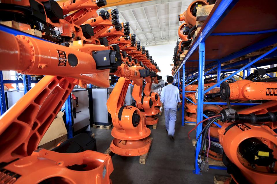 Un trabajador pasea entre una fila de robots en una fábrica de Shanghai. REUTERS/Aly Song/Files