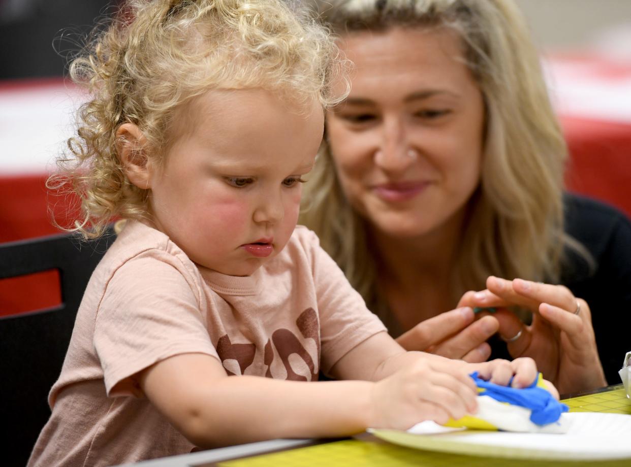 Harlow Wilson, 2, mixes colors with clay as her mother, Chelsea Wilson of North Canton, watches during a Family Art Party at the North Canton Public Library.